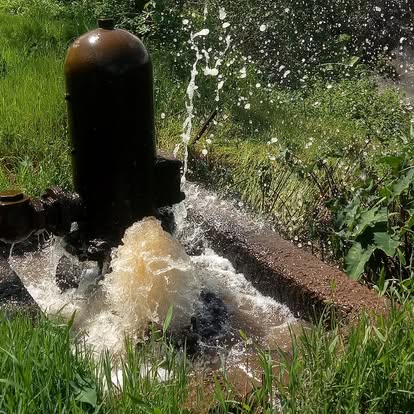 Hydram pump running in the field with water spraying from the waste valve