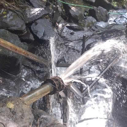 High-pressure water jet from hydram waste valve on rocky stream bed